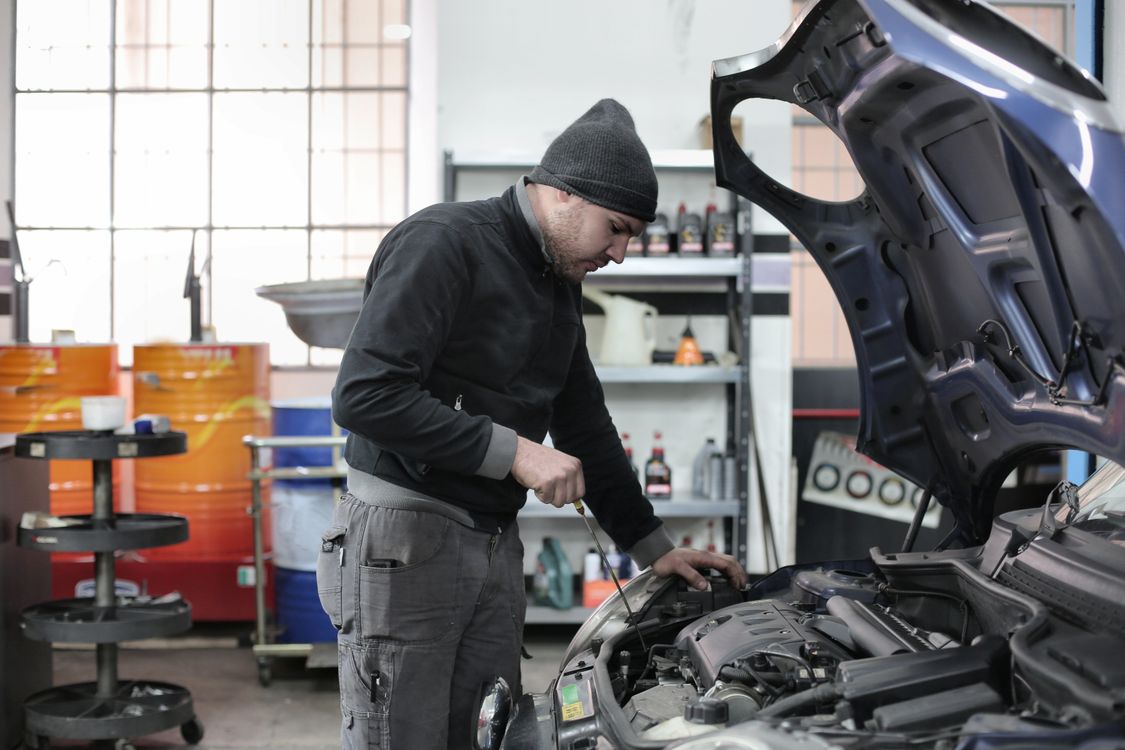 Mécanicien ouvrant le bouchon de remplissage d'huile d'un moteur automobile