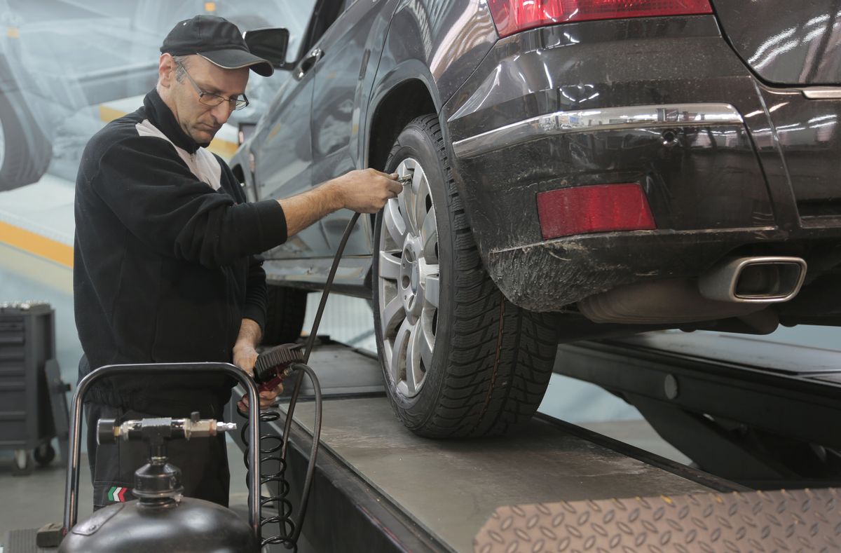Technicien vérifiant la pression d'un pneu dans un centre auto