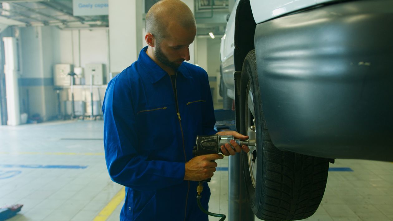 Technicien retirant un pneu avec une clé pneumatique en atelier