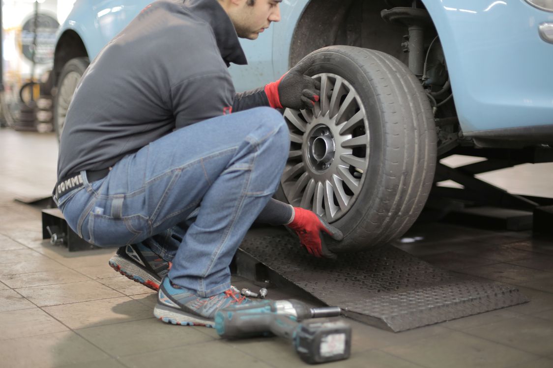 Mécanicien changeant un pneu de voiture en atelier avec une clé